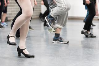 Drei Tänzer mit unterschiedlichen Schuhen, die man nur mit Beinen sieht.