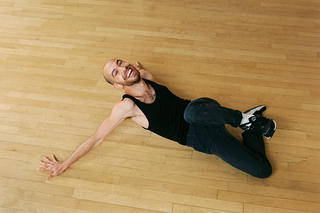 Ein junger Mann liegt lachend auf dem Tanzboden