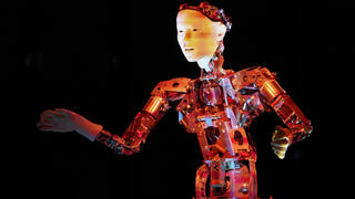 Ein humanoider Roboter mit künstlicher Intelligenz steht als Dirigent auf der Bühne.