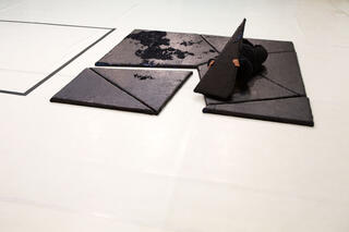 Schwarze Platten in Dreiecksform auf einer weißen Bühne.