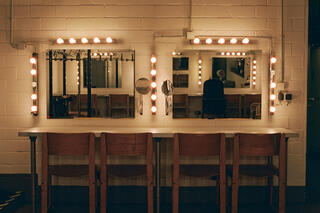 Zwei nebeneinander hängende Spiegel, davor ein langer Tisch mit vier Stühlen.
