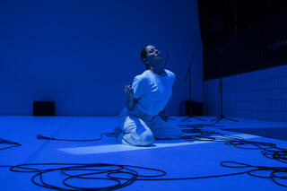 Tänzerin sitzt auf dem Boden in blauem Licht