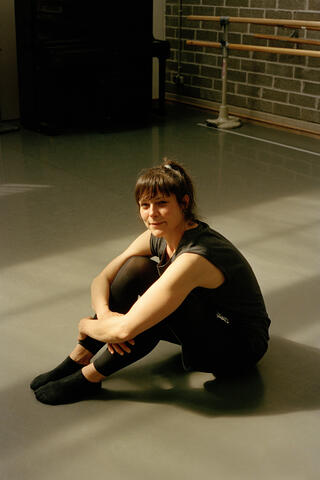 Laura Wolff sitzt auf dem Boden des Tanzstudios und blickt in die Kamera