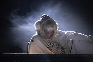 Person hat den Kopf gesenkt und die Augen geschlossen. Der Hintergrund ist im düsteren Nebel.