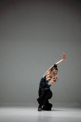 das Bild zeigt eine Person in einer hockenden Position. Sie hat die Arme über sich und nach vorne gestreckt.