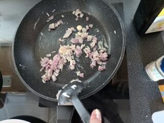 Das Bild zeigt eine Pfanne auf dem Herd. In dieser Pfanne werden Zwiebeln gebraten.