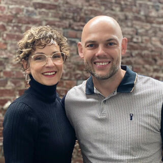 Eine Frau und ein Mann stehen vor einer Backsteinwand.