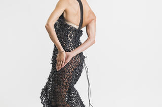 Vanesa Aibar trägt ein langes schwarzes Kleid und hat die Hände hinter Ihrem Rücken gefaltet.