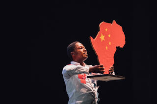 Panaibra Canda hält eine Statue in der Form von Afrika hoch, die wie die chinesische Flagge bemalt ist.