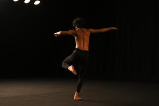 Sorour Darabi tanzt auf einer dunklen Bühne.