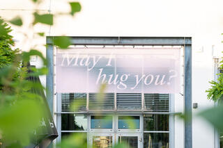 Banner May I hug you? am Eingang des tanzhaus nrw