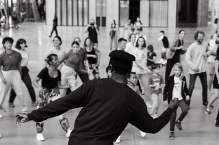 Eine Gruppe von Performer*innen tanzt im öffentlichen Raum.