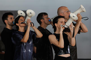 Eine Gruppe Tänzerinnen spricht in Megaphone