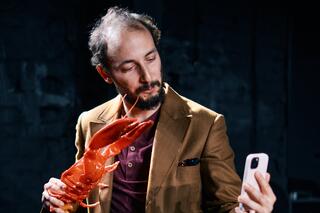 Auf dem Foto ist der Performer Francesco D’Amelio zu sehen, wie er ein Foto von sich macht während er einen Hummer in der Hand hält.